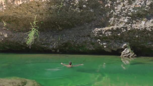 Attraktiver Mann springt kopfüber ins glasklare Wasser und schwimmt im Fluss. Sommerstimmung und Urlaubskonzept. 