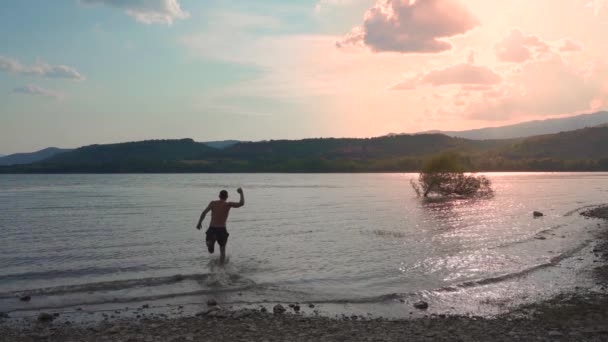 迷人的男人头朝前跑 跳入晶莹清澈的水中 慢吞吞地在河里游泳 夏天的感受和假期的概念 — 图库视频影像
