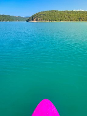 Çekici ve güçlü bir adam gölde şeffaf suların tadını çıkarıyor. Tropik seyahat, seyahat tutkusu ve su aktivitesi konsepti. Paddle Surf su sporları. Yaz tatilleri.