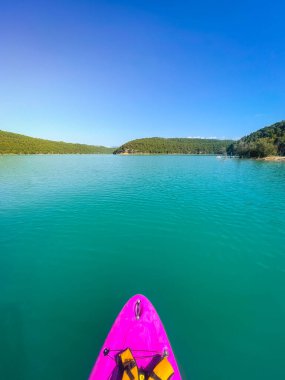 Çekici ve güçlü bir adam gölde şeffaf suların tadını çıkarıyor. Tropik seyahat, seyahat tutkusu ve su aktivitesi konsepti. Paddle Surf su sporları. Yaz tatilleri.