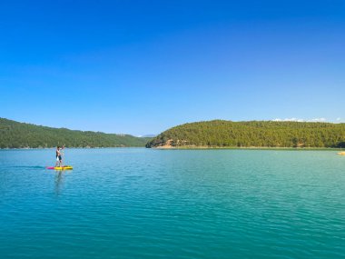 Çekici ve güçlü bir adam gölde şeffaf suların tadını çıkarıyor. Tropik seyahat, seyahat tutkusu ve su aktivitesi konsepti. Paddle Surf su sporları. Yaz tatilleri.