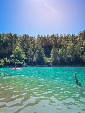 Çekici ve güçlü bir adam gölde şeffaf suların tadını çıkarıyor. Tropik seyahat, seyahat tutkusu ve su aktivitesi konsepti. Paddle Surf su sporları. Yaz tatilleri.