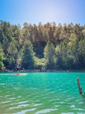 Çekici ve güçlü bir adam gölde şeffaf suların tadını çıkarıyor. Tropik seyahat, seyahat tutkusu ve su aktivitesi konsepti. Paddle Surf su sporları. Yaz tatilleri.