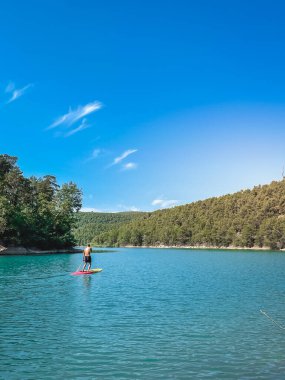 Çekici ve güçlü bir adam gölde şeffaf suların tadını çıkarıyor. Tropik seyahat, seyahat tutkusu ve su aktivitesi konsepti. Paddle Surf su sporları. Yaz tatilleri.