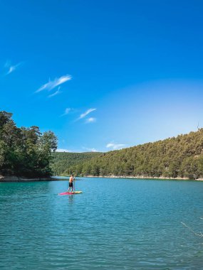 Çekici ve güçlü bir adam gölde şeffaf suların tadını çıkarıyor. Tropik seyahat, seyahat tutkusu ve su aktivitesi konsepti. Paddle Surf su sporları. Yaz tatilleri.