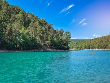 Çekici ve güçlü bir adam gölde şeffaf suların tadını çıkarıyor. Tropik seyahat, seyahat tutkusu ve su aktivitesi konsepti. Paddle Surf su sporları. Yaz tatilleri.