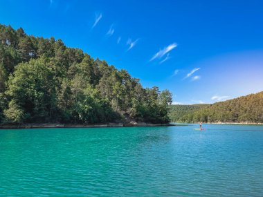 Çekici ve güçlü bir adam gölde şeffaf suların tadını çıkarıyor. Tropik seyahat, seyahat tutkusu ve su aktivitesi konsepti. Paddle Surf su sporları. Yaz tatilleri.