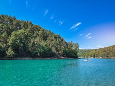 Çekici ve güçlü bir adam gölde şeffaf suların tadını çıkarıyor. Tropik seyahat, seyahat tutkusu ve su aktivitesi konsepti. Paddle Surf su sporları. Yaz tatilleri.