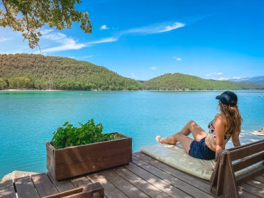 Gölde bir kanepede oturan güzel bir kadın. Gün batımında muhteşem bir manzara. Hayalperest adam ayakta ve gölü izliyor. Doğa kavramının güzelliği. Seyahat ve tatil kavramı.