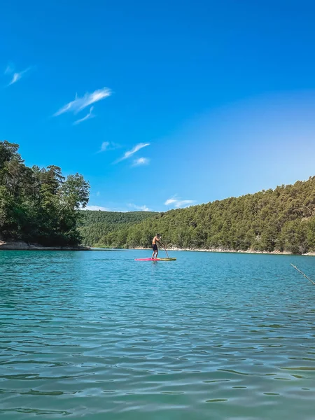Çekici ve güçlü bir adam gölde şeffaf suların tadını çıkarıyor. Tropik seyahat, seyahat tutkusu ve su aktivitesi konsepti. Paddle Surf su sporları. Yaz tatilleri.