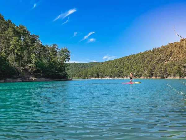 Çekici ve güçlü bir adam gölde şeffaf suların tadını çıkarıyor. Tropik seyahat, seyahat tutkusu ve su aktivitesi konsepti. Paddle Surf su sporları. Yaz tatilleri.