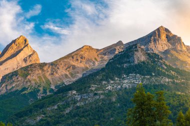 Gün batımında güzel dağlar manzarası. Dağların üzerinde renkli bir gökyüzünün manzarası. Turuncu ve mavi bulutlar. Macera yolculuğu konsepti. Duvar kağıdı arka plan doğa baskısı.