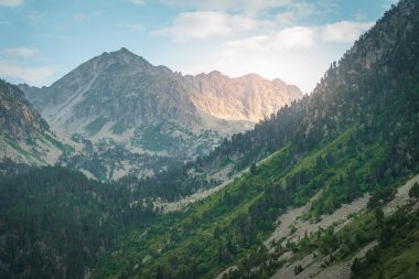 Gün batımında güzel ve dramatik dağlar. Dağların üzerinde renkli bir gökyüzünün manzarası. Turuncu ve mavi bulutlar. Macera yolculuğu konsepti. Duvar kağıdı arka plan doğa baskısı.