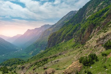 Gün batımında güzel dağlar manzarası. Dağların üzerinde renkli bir gökyüzünün manzarası. Turuncu ve mavi bulutlar. Macera yolculuğu konsepti. Duvar kağıdı arka plan doğa baskısı.