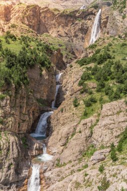 Gün batımında dağlarda güzel şelale çağlayanı. Macera yolculuğu konsepti. Duvar kağıdı arka plan doğa baskısı.