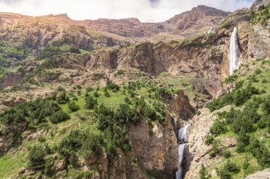 Gün batımında dağlarda güzel şelale çağlayanı. Macera yolculuğu konsepti. Duvar kağıdı arka plan doğa baskısı.