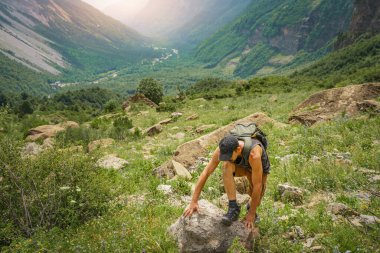 Genç adam yeşil bir dağın tepesinde gün batımında muhteşem manzara manzarasının tadını çıkarıyor. Cennet çim dağı. Yaşam tarzı rahatlama ve özgürlük. Doğa kavramının güzelliği.