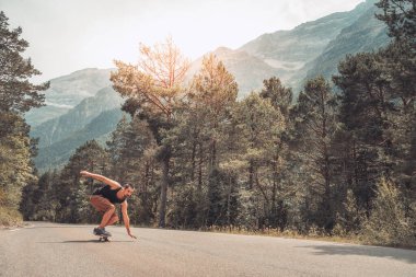 Hippi uzun zamandır virajlı bir dağ yolunda. Paten ve uzun tahta sporları. Özgürlük ve hız kavramı.