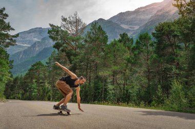 Hippi uzun zamandır virajlı bir dağ yolunda. Paten ve uzun tahta sporları. Özgürlük ve hız kavramı.
