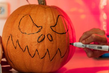 Kabak suratlı kadın Cadılar Bayramı 'nda balkabağı yüzünü boyuyor ve balkabağı tarafı hazırlıyor. Cadılar Bayramı için hazırlanıyorum. Mutfakta balkabaklarıyla eğleniyorum..