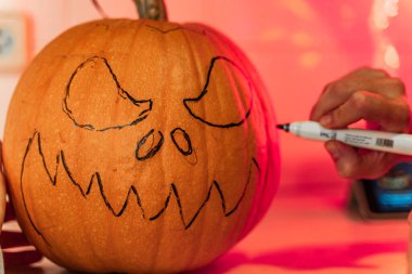 Kabak suratlı kadın Cadılar Bayramı 'nda balkabağı yüzünü boyuyor ve balkabağı tarafı hazırlıyor. Cadılar Bayramı için hazırlanıyorum. Mutfakta balkabaklarıyla eğleniyorum..