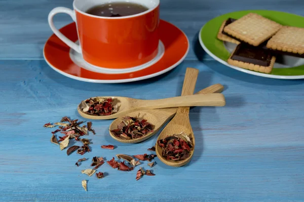 Çay fincanı ve mavi masadaki ahşap kaşık yapraklarının görüntüsü