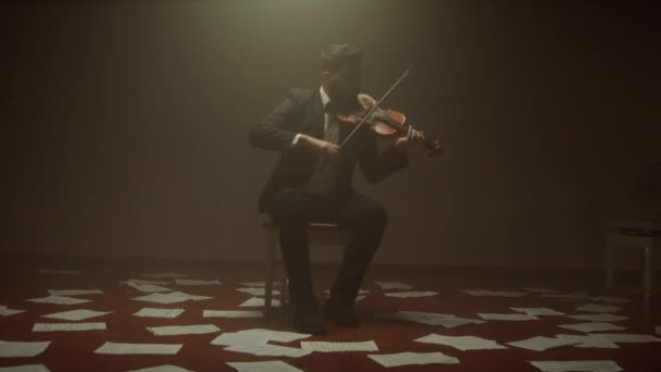 Violinisten spelar fiol ensam på scenen, anteckningar på golvet — Stockvideo