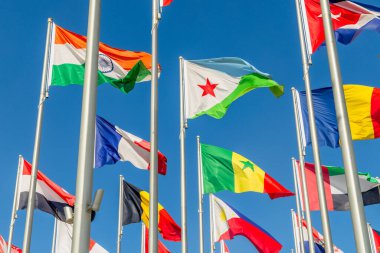 Önplanda Cibuti, Fransız, Hint, Rumen ve Senegal afişleri, Doha, Katar olmak üzere pek çok dünya ülkesinin ulusal bayrakları dalgalanırken,