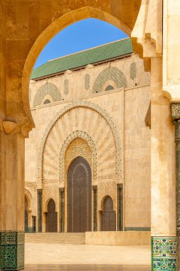 Hasan II Camii, Kazablanka, Fas 'ın dekore edilmiş portalı, geometrik desenleri ve taş cephesini gösteren kemerli bir bakış açısı.