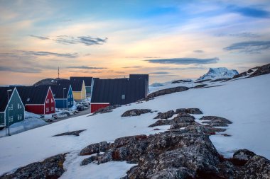 Renkli evleri, karları, kayaları ve yumuşak akşam ışıklarıyla kutup kıyısı yerleşimi, soğuk okyanus fiyortu Nuuk, Grönland 'daki Grönland Inuit mirası ve kuzey mimarisini yansıtıyor.