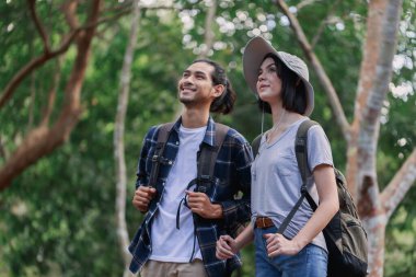 Ormanda yürüyüş yapan mutlu bir çift. Aktif genç Kafkas kadın yürüyüşçü ve Asyalı erkek.
