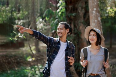 Ormanda yürüyüş yapan mutlu bir çift. Aktif genç Kafkas kadın yürüyüşçü ve Asyalı erkek.
