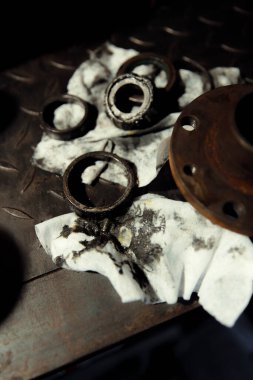 Klasik bir arabaya tekerlek yerleştirmek. Eski araç yenileme konsepti. Kirli, yağlı bir peçeteye takılmış yıpranmış tekerlek. Metal desenli arkaplan.