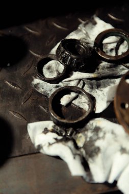 Klasik bir arabaya tekerlek yerleştirmek. Eski araç yenileme konsepti. Kirli, yağlı bir peçeteye takılmış yıpranmış tekerlek. Metal desenli arkaplan.