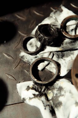 Klasik bir arabaya tekerlek yerleştirmek. Eski araç yenileme konsepti. Kirli, yağlı bir peçeteye takılmış yıpranmış tekerlek. Metal desenli arkaplan.