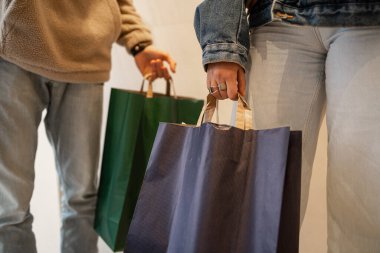 Sokakta alışveriş yapan genç insanların kağıt alışveriş torbalarıyla görüntüsü. Alışveriş ve tüketim kavramı.