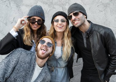 Tuhaf suratlar ve alışılmadık suratlarla poz veren gençlerin portresi. Moda milenyumları, açık havada şakalaşarak eğleniyor..