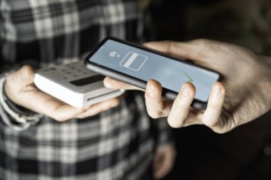 Akıllı telefondan elektronik ödeme. El ele tutuşan cep telefonları NFC üzerinden para transferini gittikçe daha az kablosuz hale getiriyor. Parmaklarına odaklan.