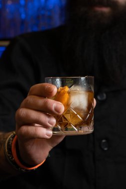 Tanınmayan bir barmen bir bardak Negroni 'ye buz ve limonlu kokteyl veriyor..