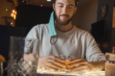 Sakallı, maskeli, bar tezgahında alkollü bir içecekle mutlu bir hayat süren adam. Gençler için yeni normal davranışlar kavramı.
