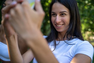 Esmer kız akıllı telefonuyla parkta selfie çekiyor.