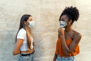 Coronavirus kilitlenmesinden sonra yüz maskesi takmış çok ırklı arkadaşlar konuşuyor.