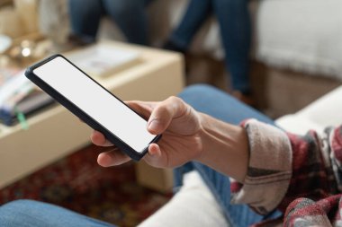 Kanepede akıllı telefonunu kullanan bir kadın. Yakın plan fotoğraf.