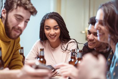 Arkadaş ziyafet için toplanıyor. Neşeli gençlik, akıllı telefon ekranlarını izlemek ve bira içmek gibi olumlu duyguları paylaşıyor. Çok ırklı gençler bira içip sosyal medya uygulaması kullanarak eğleniyorlar.