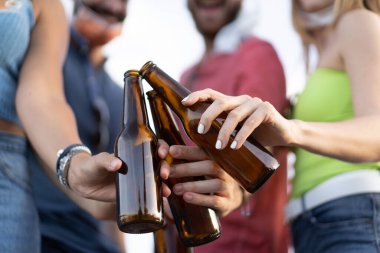 Koronavirüs çöküntüsü sırasında gençlerin dışarıda bira şişeleriyle kadeh kaldırması ve düşük yüz maskeleri takması gibi normal bir hayat tarzı.