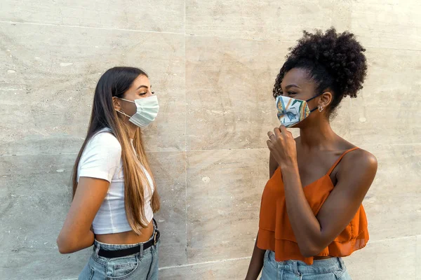 Coronavirus kilitlenmesinden sonra yüz maskesi takmış çok ırklı arkadaşlar konuşuyor.