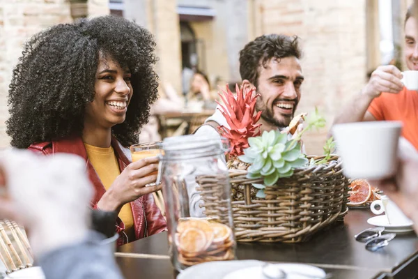 Kafede kahve, kapuçino ve meyve suyu içerek eğlenen çok ırklı bir grup insan. Milenyum kuşağı dostluğu ve olumlu duygu kavramı. Gülen Afro-Amerikalı kadına odaklan..