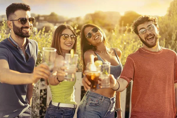 夏に屋外でカクテルグラスをクリックする若者のグループ 屋外カフェでお酒を飲みながら一緒に時間を楽しむ仲間の集まり — ストック写真