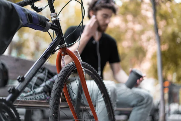 Hippi adam kenarda oturup Amerikan kahvesi içiyor ve kulaklıkla müzik dinliyor..