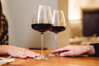 Masada iki şarap kadehi şıngırdıyor. Sevgi ve romantizm kavramı, bir restoranda buluşmalarını kırmızı şarapla kutlayan bir çift. Bardakları kapatın.